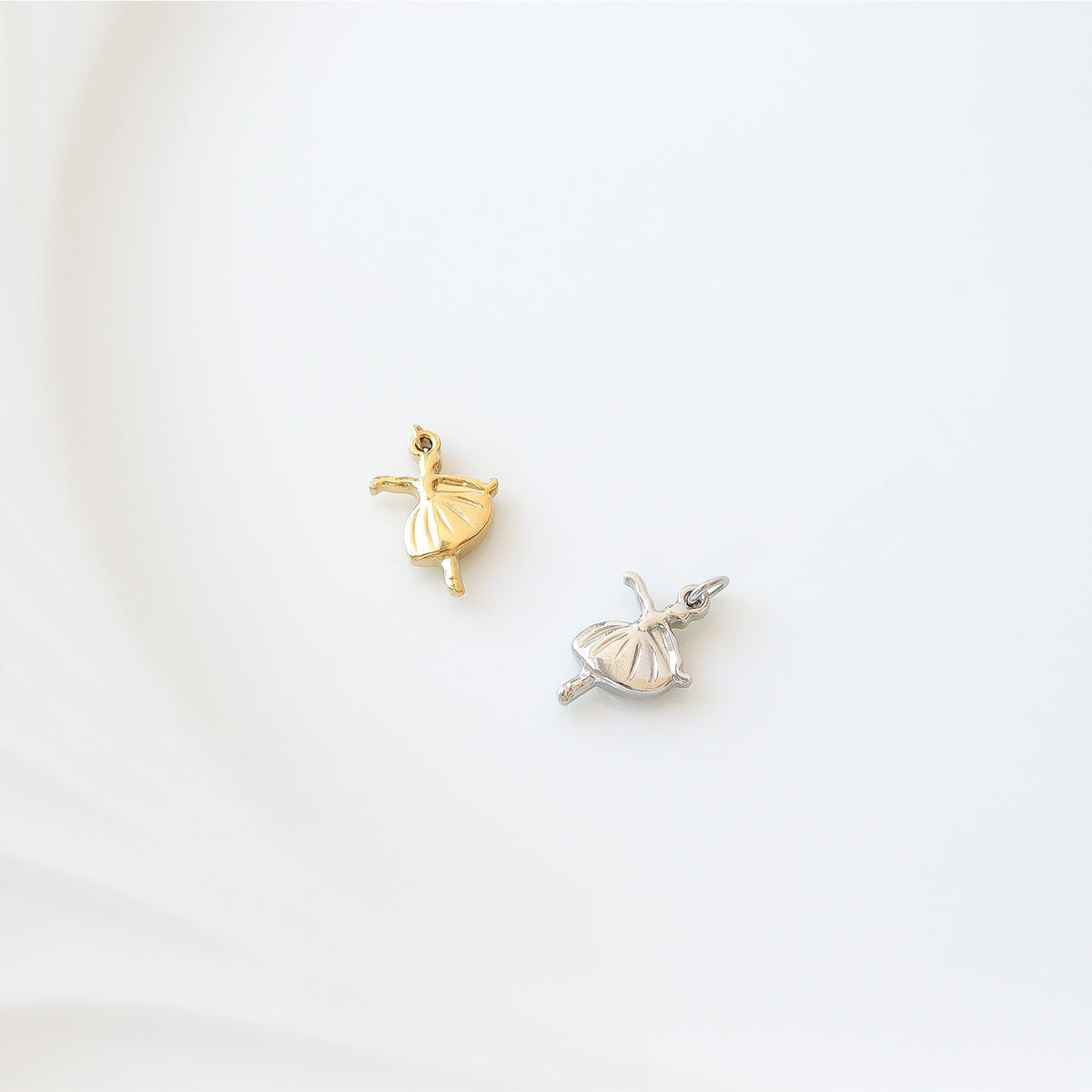 Gold and silver ballerina charms on a white background