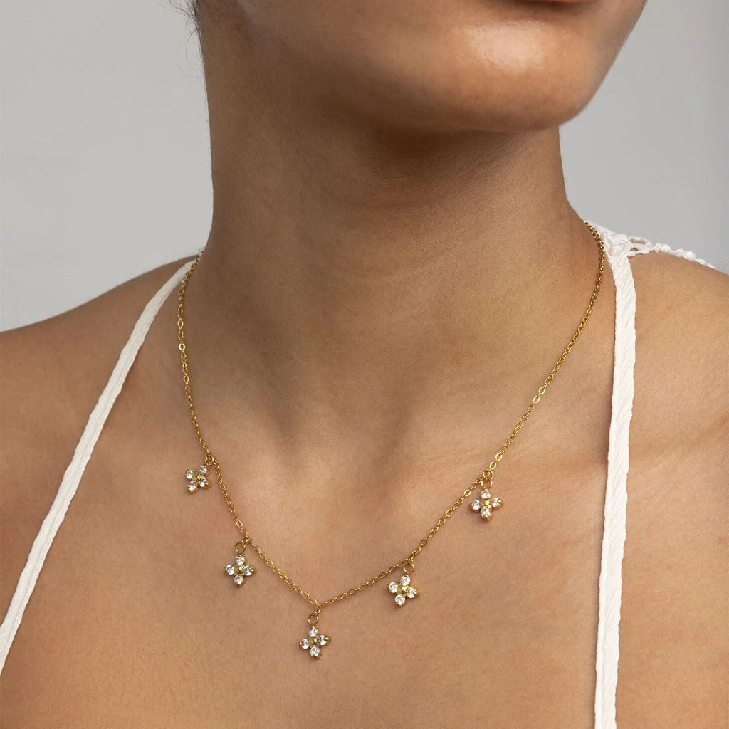 Person wearing gold CZ dangle floral necklace