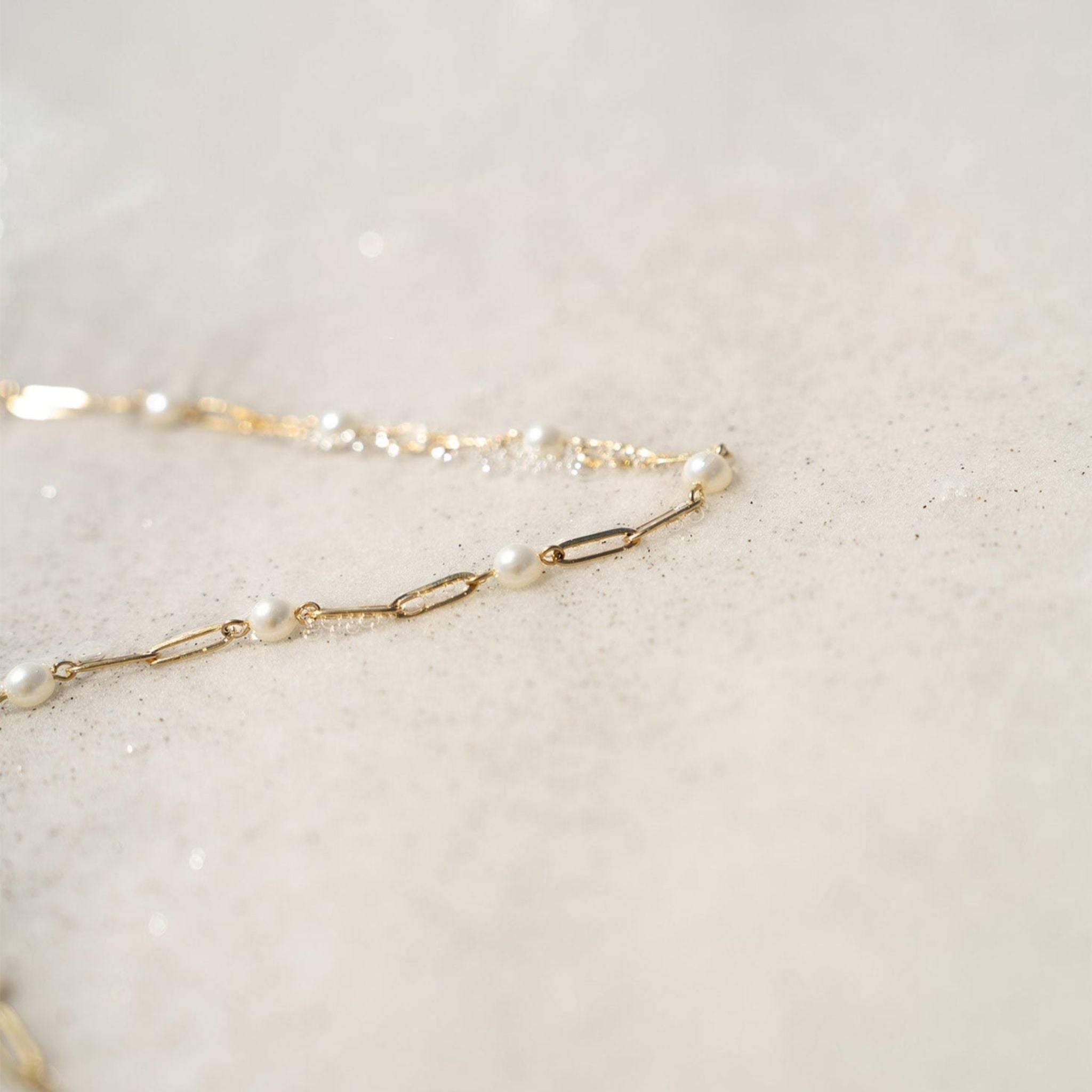 Gold chain necklace with pearls on a light beige background