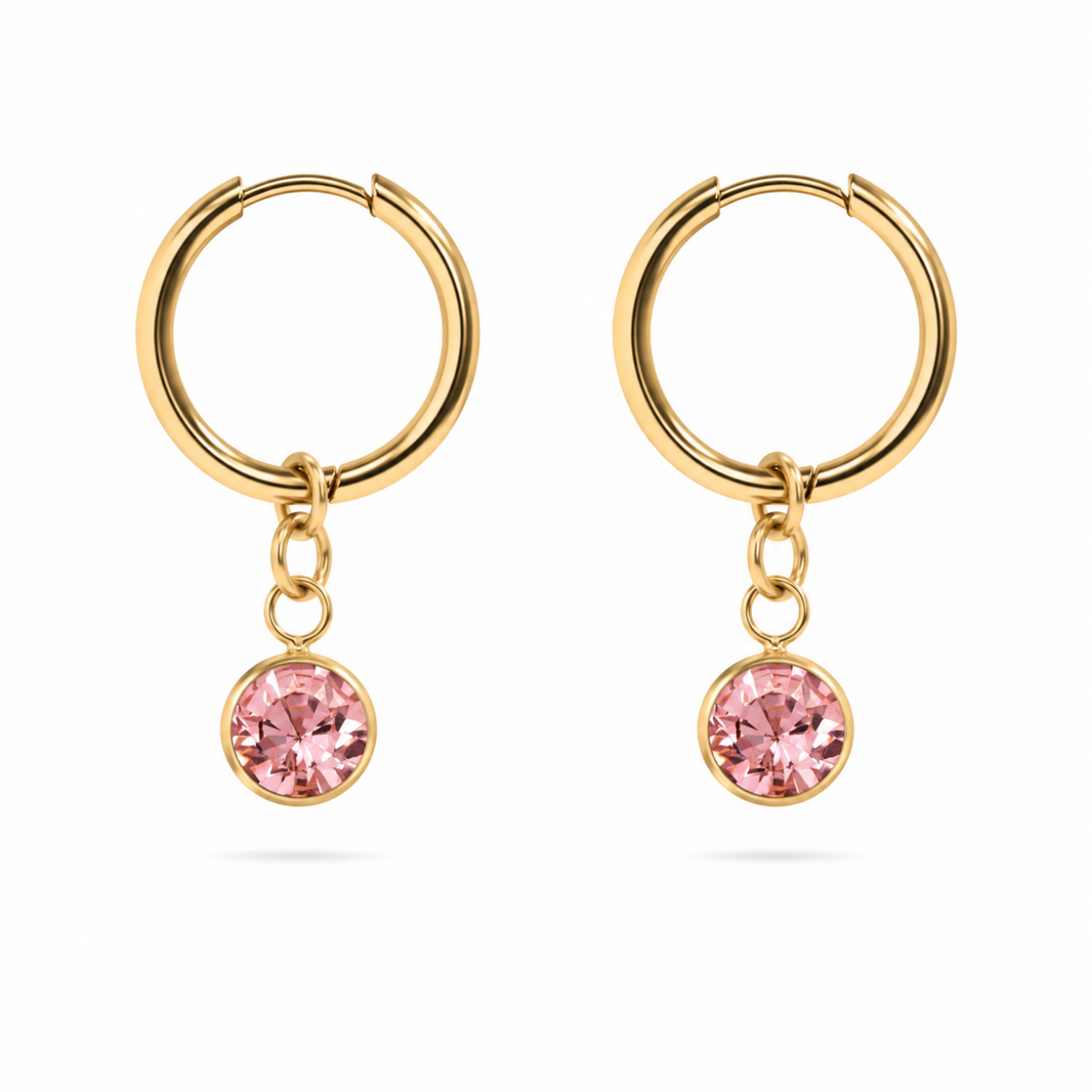 A pair of gold hoop earrings with a dangling round pink gemstone in a gold bezel setting, shown against a plain white background.