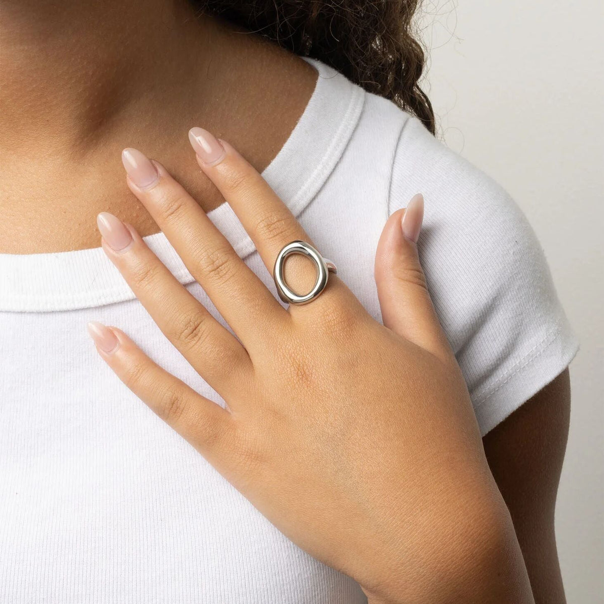 Close-up of a hand wearing a silver ring with a white background