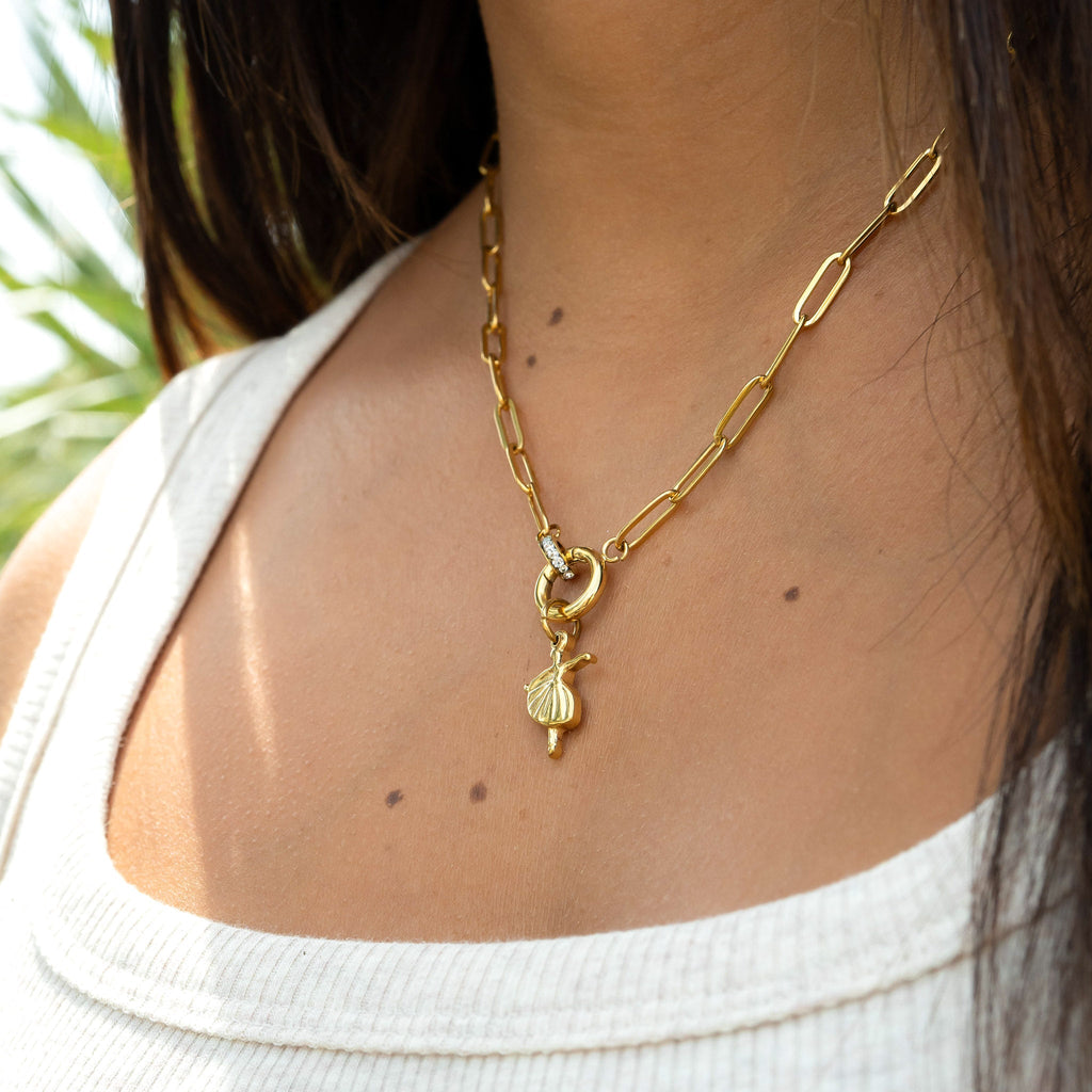 Gold necklace with a pendant worn by a person, with a blurred background