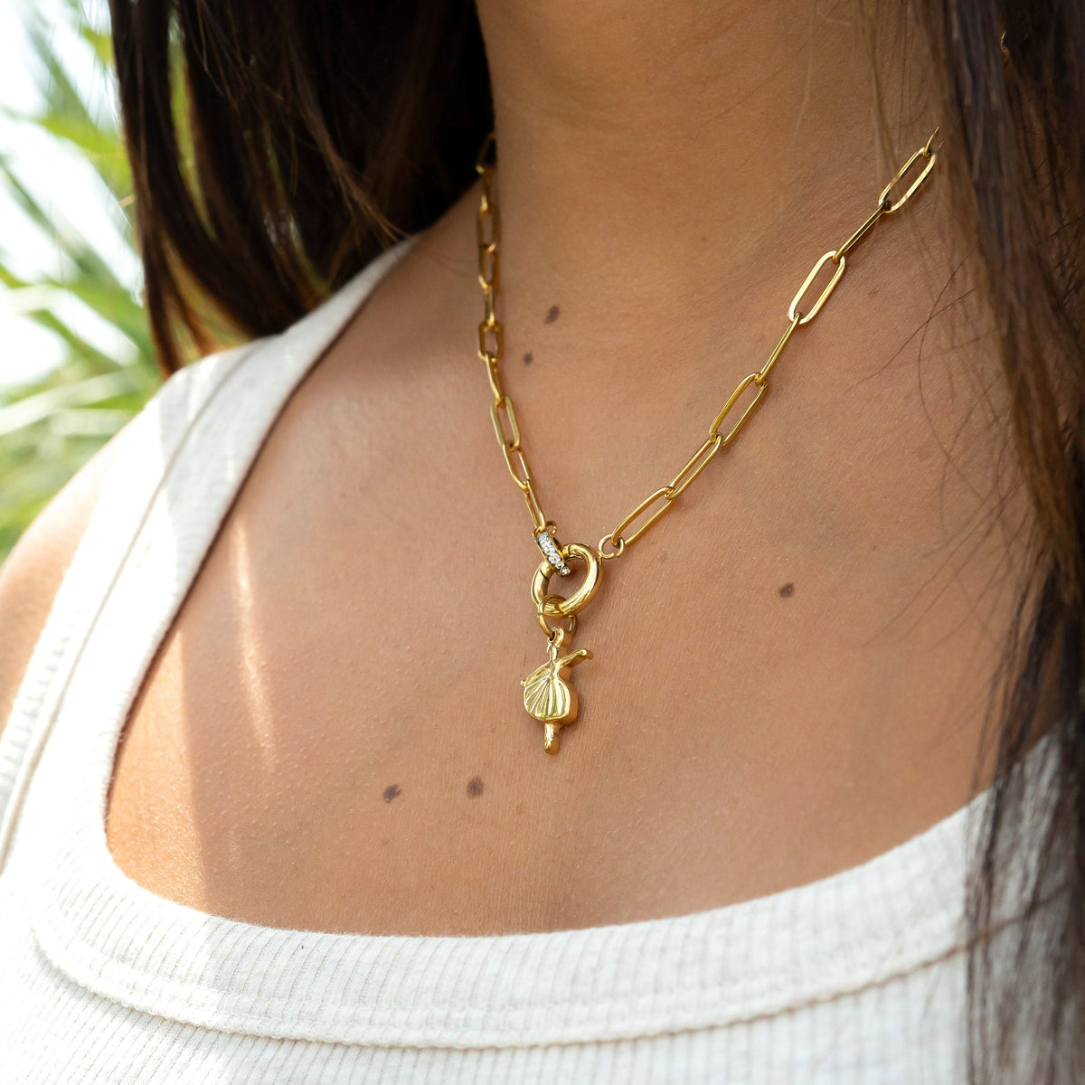 Gold necklace with a pendant worn by a person, with a blurred background