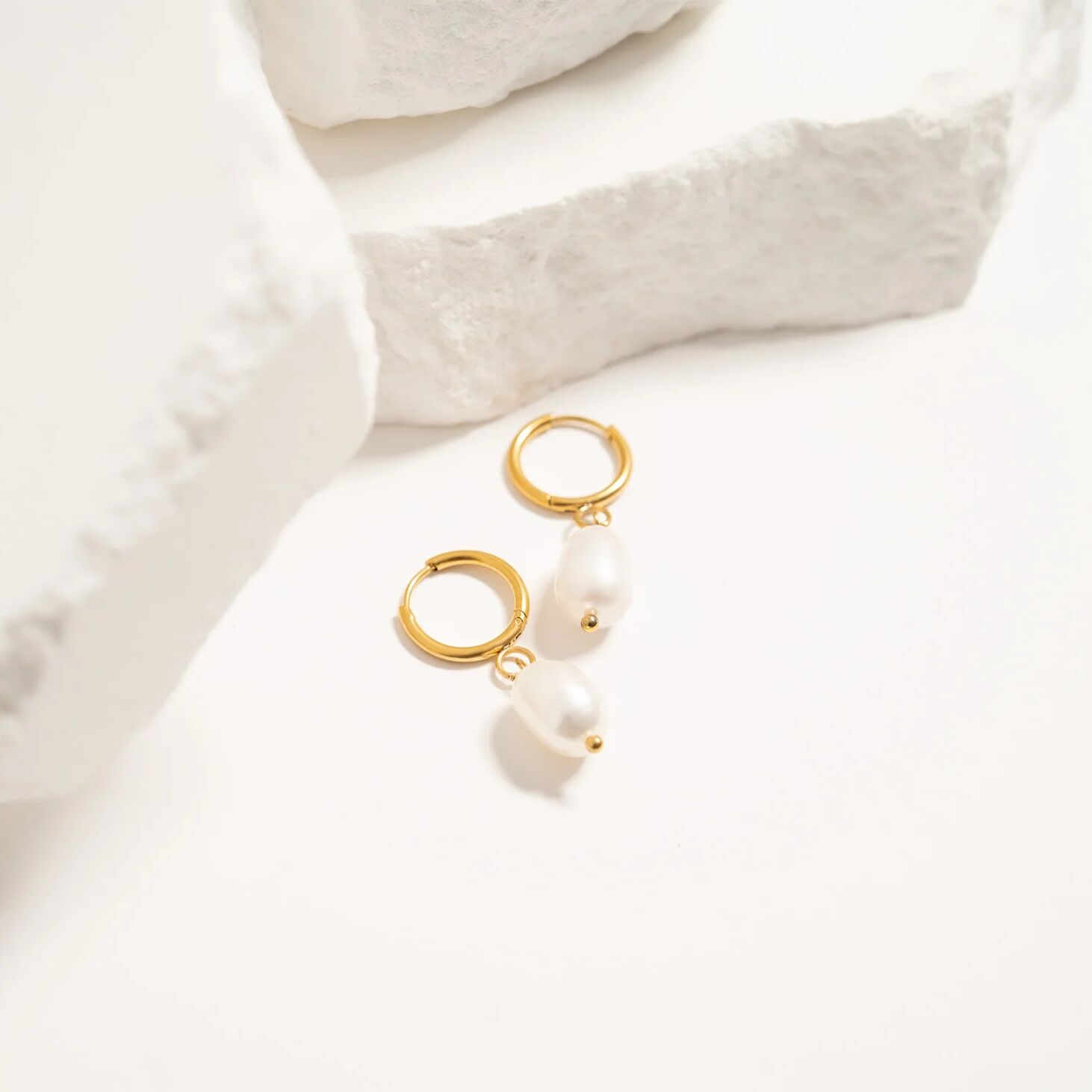 Gold hoop earrings on a white fabric background