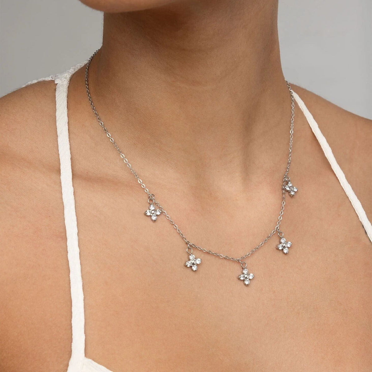 Person wearing silver dangle floral necklace
