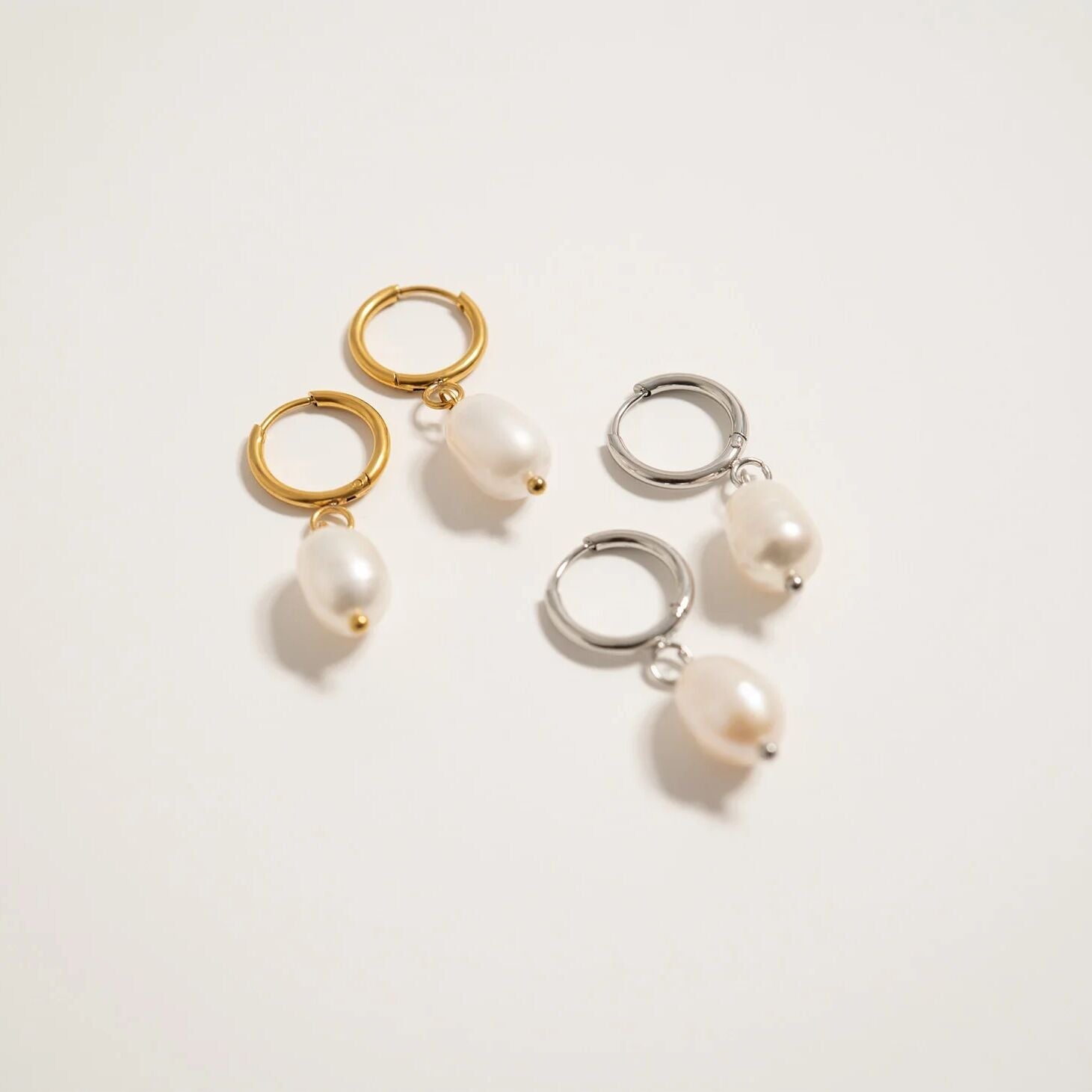 Pair of hoop earrings with pearl drops on a light background