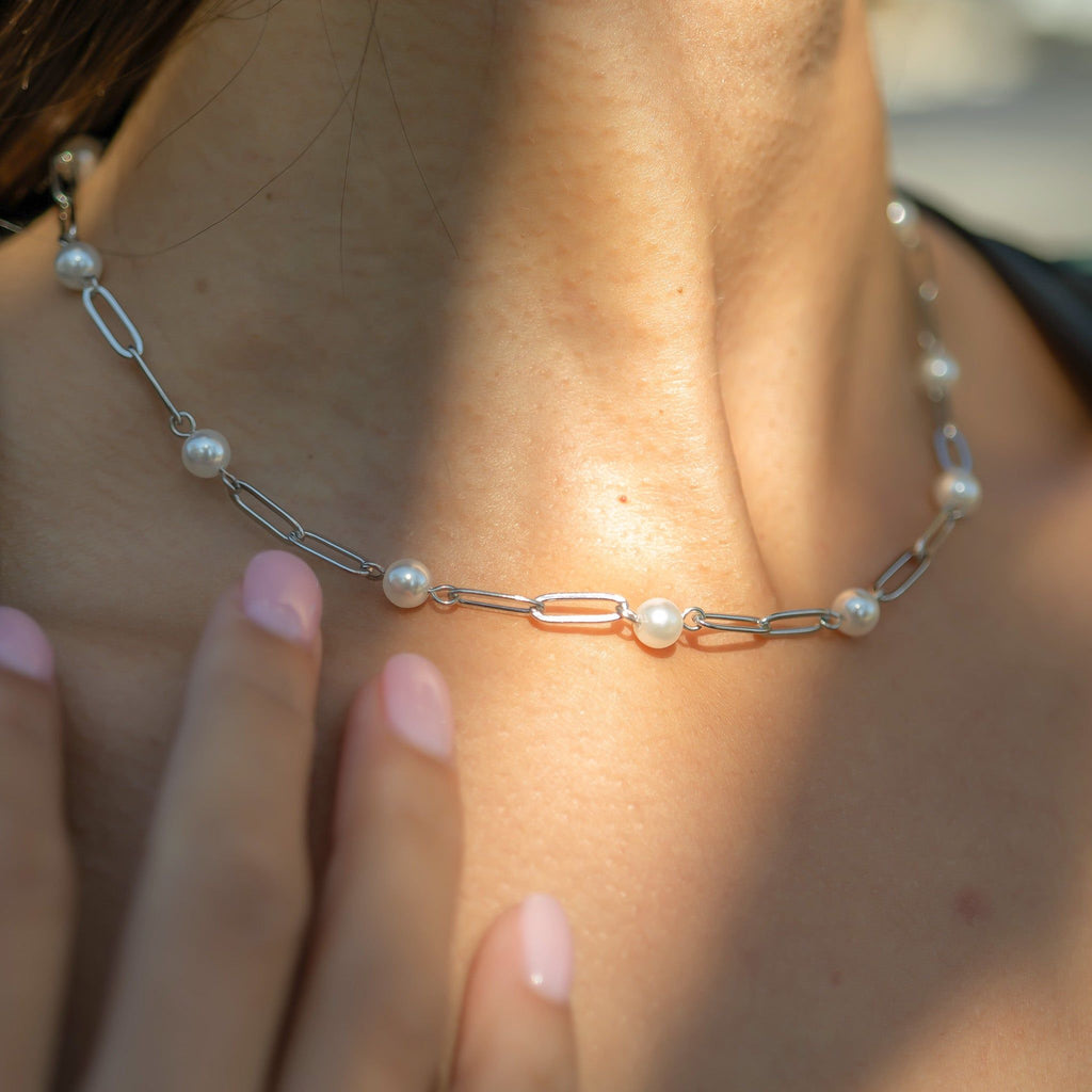 Pearl and chain bracelet on a wrist with a blurred background