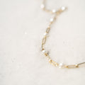 Gold necklace with pearls on a light gray background
