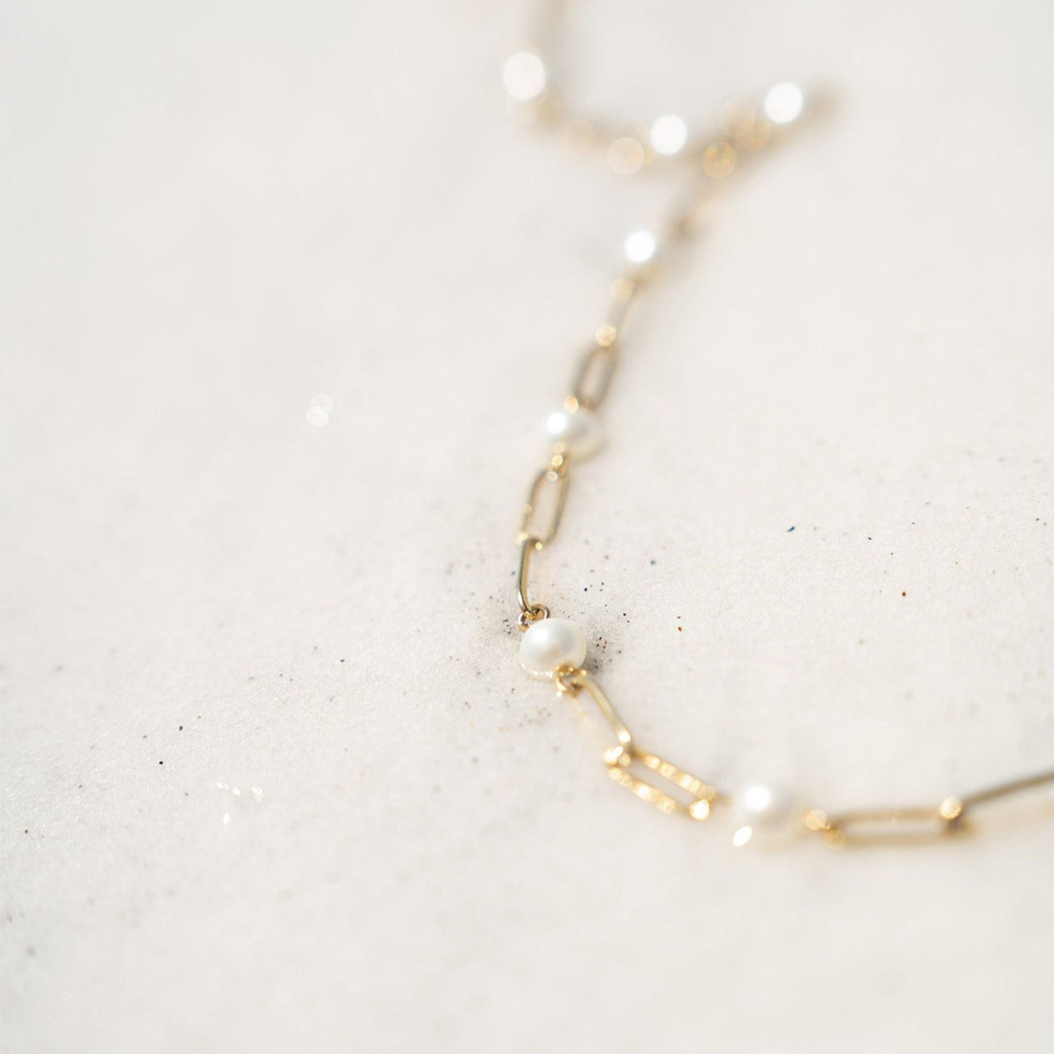 Gold necklace with pearls on a light gray background