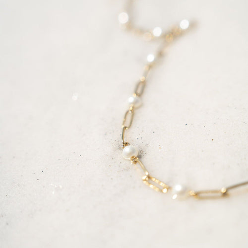 Gold necklace with pearls on a light gray background