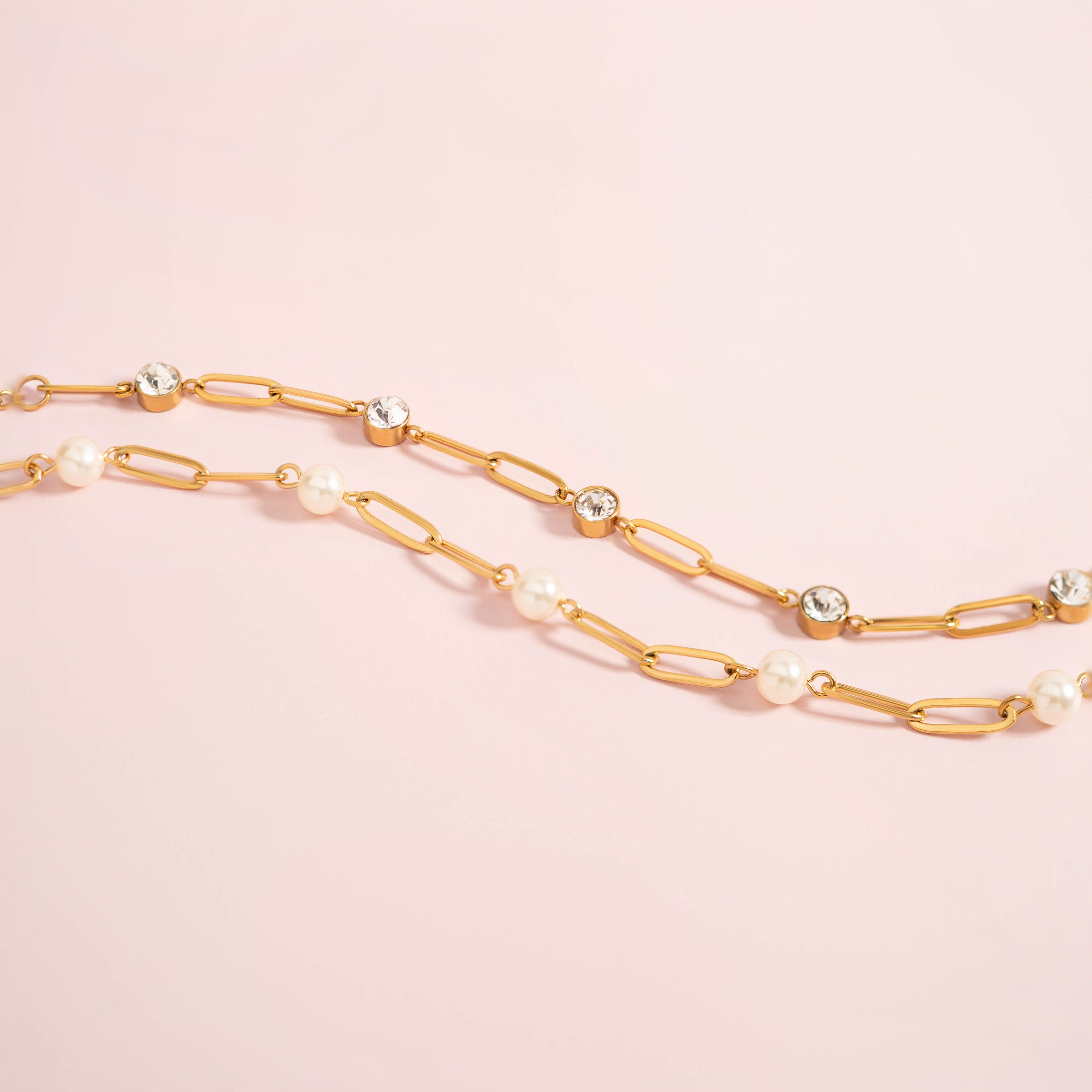 Gold chain necklace with pearls on a pink background
