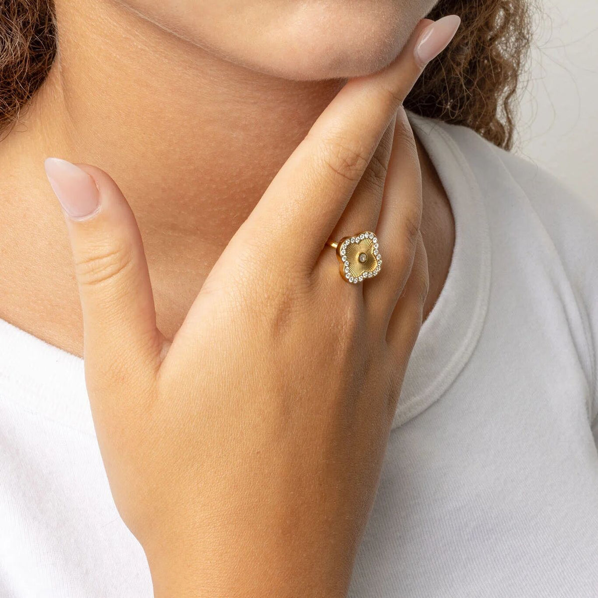 Hand wearing gold floral motif stacking ring