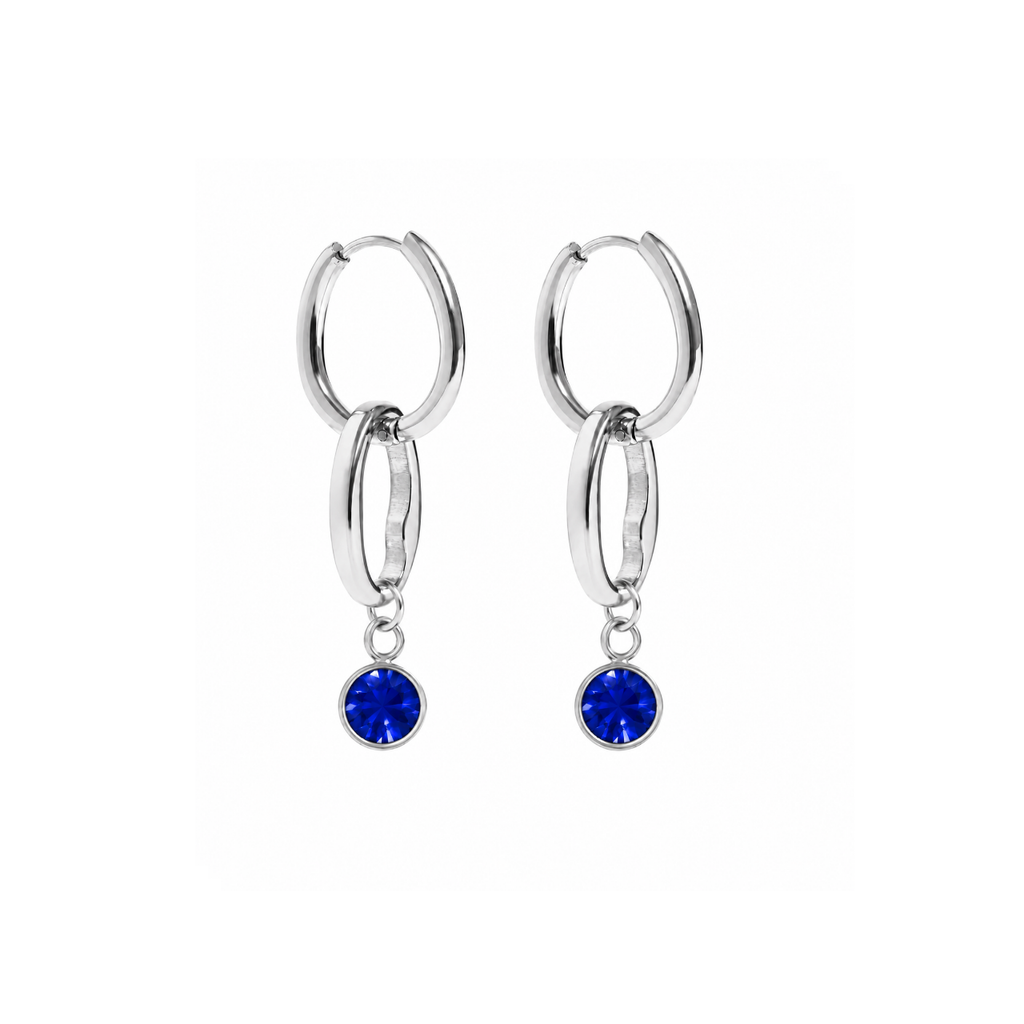 A pair of silver hoop earrings with a double-ring design and a dangling round blue gemstone, shown on a plain white background.