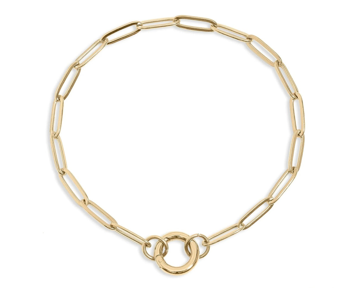 A gold paperclip chain bracelet with a double-ring charm holder clasp, displayed on a clean white background.