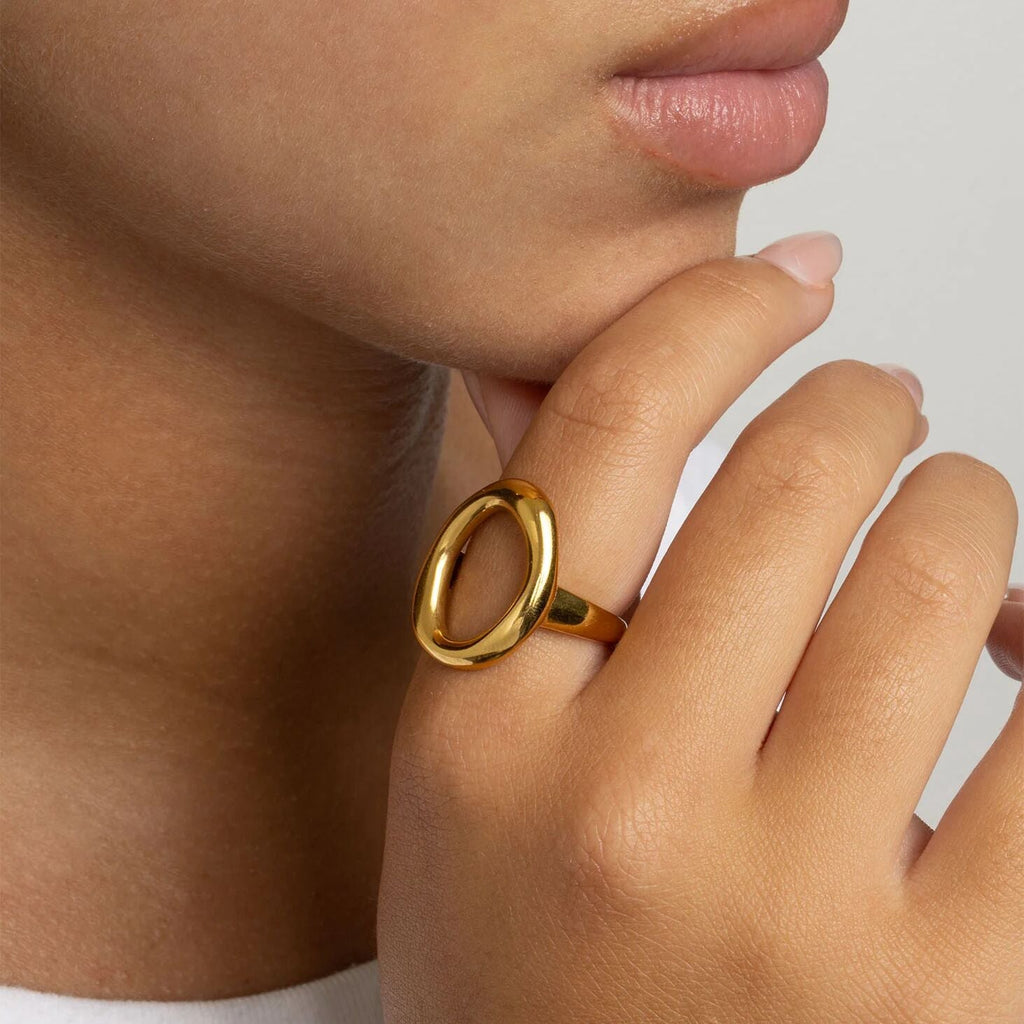 Close-up of a hand wearing a gold ring with a plain background
