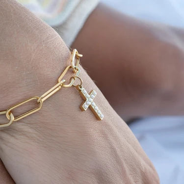 Gold bracelet with a cross charm on a wrist