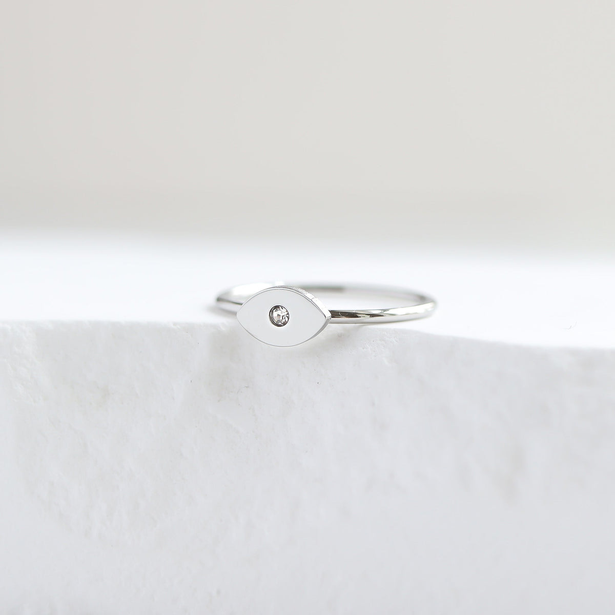Silver evil eye  ring with a small diamond on a white surface