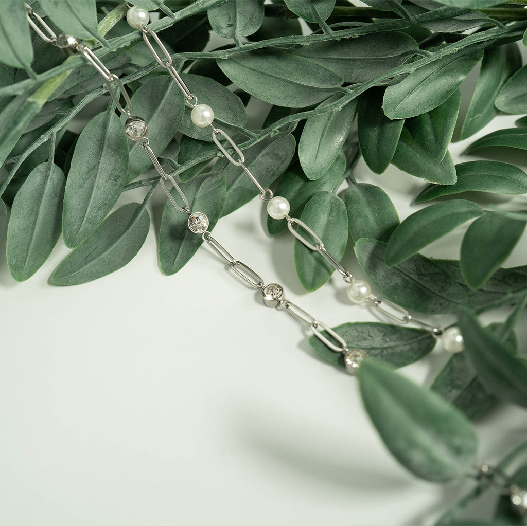 Silver chain with pearls on a green leaf background