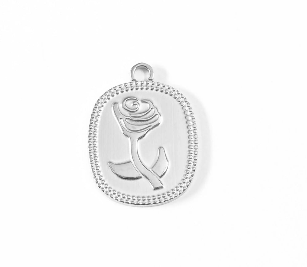 A silver oval pendant charm featuring an embossed rose design and a beaded border, shown on a clean white background.