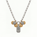 The Daphne Necklace from Garden District Jewelry New Orleans. A silver paperclip chain necklace featuring a multi-charm pendant with gold and silver evil eye coins and a central silver celestial pendant, shown on a plain white background.
