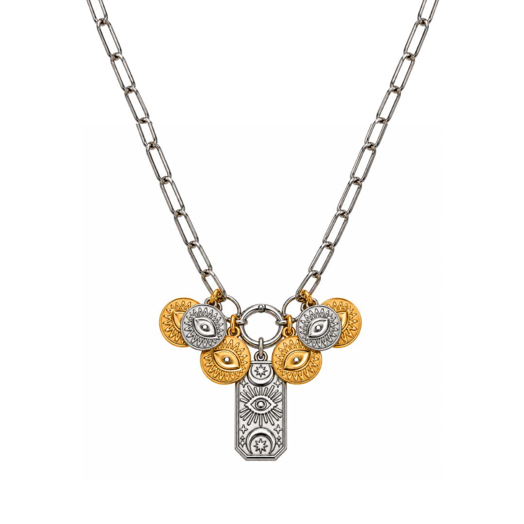 The Delphine Necklace from A silver paperclip chain necklace featuring a multi-charm pendant with gold and silver evil eye coins and a central silver celestial pendant, shown on a plain white background.arden District Jewelry.